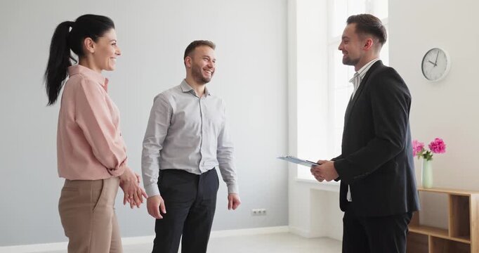 Realestate agent and couple handshake indoors. Buyers and clients meet a realtor in an apartment at a meeting to discuss agreement and purchase or rental. Concept of trust and success.