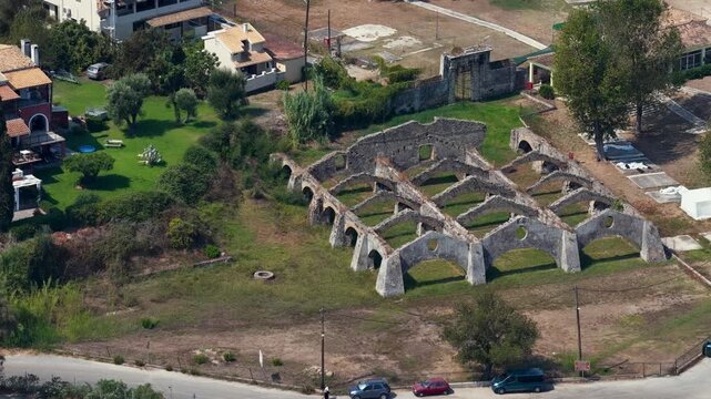 Aerial drone view of historic Venetian Arsenal ruins in Gouvia, Corfu Island, Greece. Old stone shipyard arches surrounded by green landscape