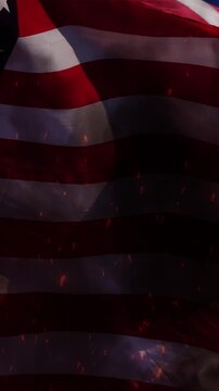 American flag waving against blue sky burning, with the smoke and particles of fire visible