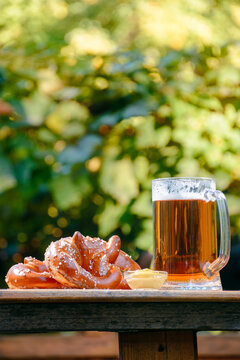 beer and pretzel on a wooden plank. outdoor scenery. oktoberfest holiday design background