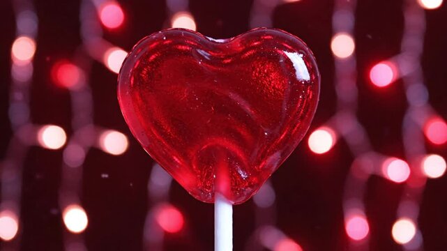 Heart-shaped lollipop with a red background and soft-focused string lights create a romantic mood