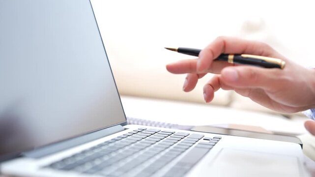 Business employee reviewing laptop screen with pen, typing on keyboard and using smartphone, digital technology workflow for professional work, multitasking, productivity and online communication.