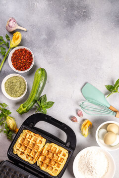 Zucchini waffles cooking in waffle maker with ingredients