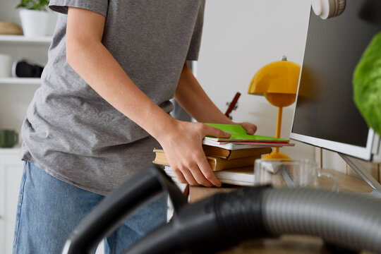 Spring cleaning and home organization, person tidying up desk with books and computer in a bright room to improve productivity and mental clarity