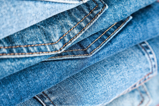 Fashion retail and sustainable clothing, stack of blue denim jeans with orange stitching showing textile texture and quality craftsmanship in a clothing store