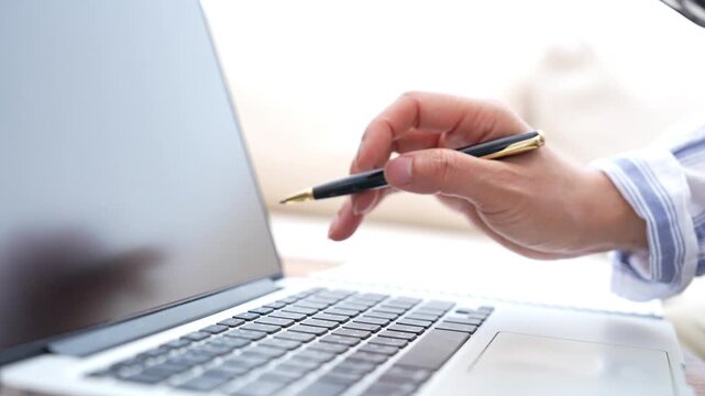 Business professional writing notes, checking laptop screen and typing on keyboard, focused digital workflow for planning, research, productivity, online work and office documentation.