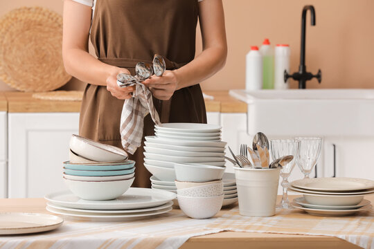 Household chores and kitchen hygiene, woman wiping clean cutlery with a towel after washing dishes in a home kitchen environment