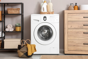 Home organization and laundry room interior, modern washing machine with detergent bottles and...