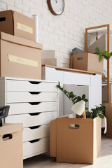 Chests of drawers with cardboard boxes near white brick wall in office on moving day