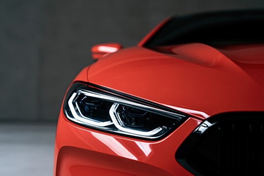 Red sports car closeup of led headlight and sculpted hood for automotive background and banner design showcasing sleek detail