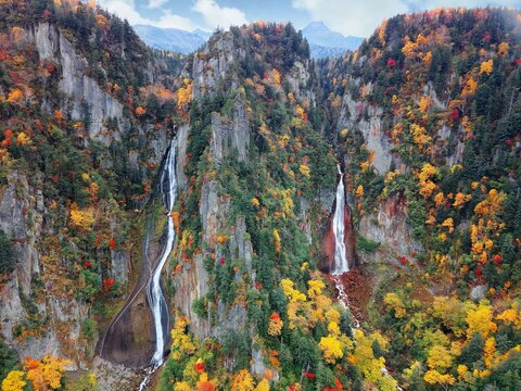 Autumn scenery of Ginga and Ryusei Waterfalls in Sounkyo Gorge, with beautiful fall colors on the rocky cliffs & majestic Kurodake mountain in background, in Daisetsuzan National Park, Hokkaido, Japan