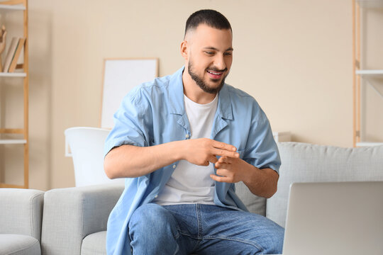 Young mute man using sign language during video call at home