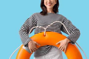 Young woman with rescue ring on blue background © Pixel-Shot