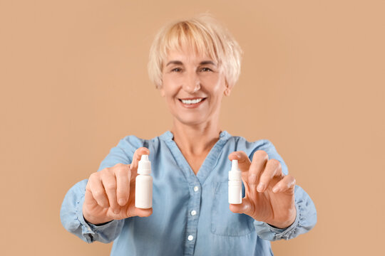 Mature woman with eye drops on beige background