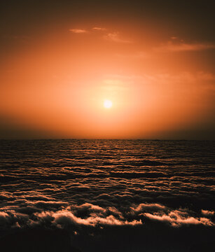 Orange sun above a rolling sea of clouds