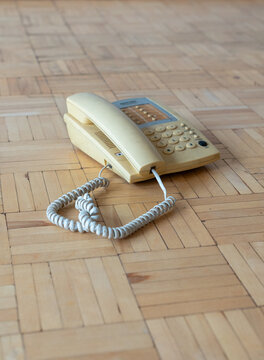 Old apartment interior with outdated landline telephone on worn parquet floor, neglected residential space requiring renovation and home refurbishment