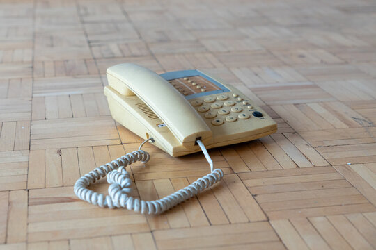 Old apartment interior with outdated landline telephone on worn parquet floor, neglected residential space requiring renovation and home refurbishment