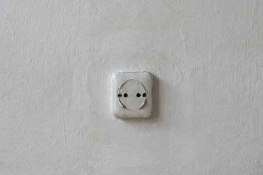 Old apartment interior with outdated electrical outlet on a worn textured wall, poor home condition and residential space requiring renovation