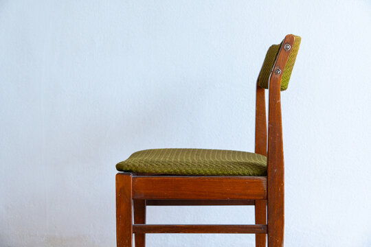 Vintage wooden chair against a worn wall in an empty apartment, outdated interior requiring renovation and remodeling