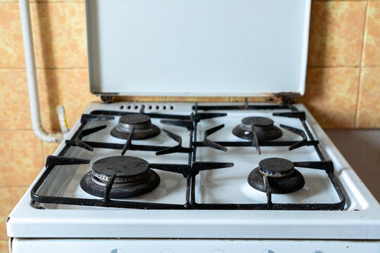 Old gas stove in an outdated apartment kitchen, worn and neglected cooking appliance with stained surfaces, representing a home requiring renovation and refurbishment