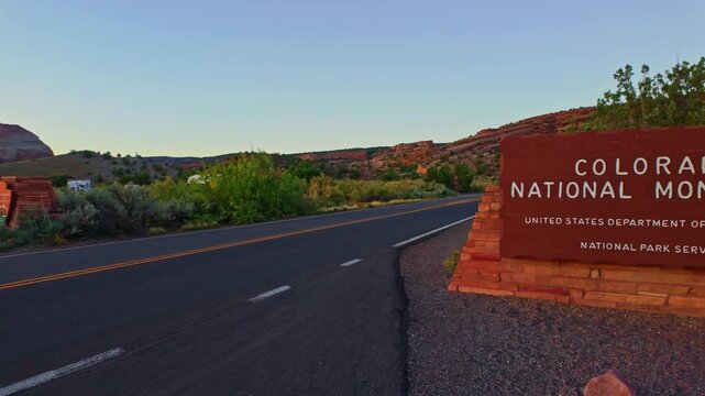 Golden dawn light strikes the rustic wooden entrance road sign welcoming visitors to Colorado National Monument near Fruita