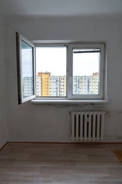 Old apartment interior in poor condition with outdated walls, exposed wiring and worn flooring, empty room requiring renovation and remodeling