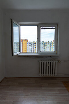 Old apartment interior in poor condition with outdated walls, exposed wiring and worn flooring, empty room requiring renovation and remodeling