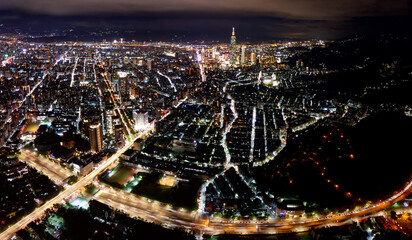 Obraz premium Aerial panorama of Taipei at night, vibrant capital city of Taiwan, with 101 Tower standing amid high-rise buildings in Xinyi Downtown and city lights of the crisscrossing streets dazzling in the dark