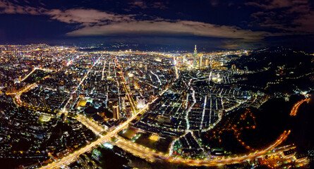 Obraz premium Aerial panorama of Taipei at night, vibrant capital city of Taiwan, with 101 Tower standing amid high-rise buildings in Xinyi Downtown and city lights of the crisscrossing streets dazzling in the dark