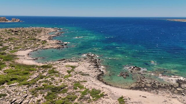 Aerial view of the Aegean sea off the coast of the island Crete in Greece. The vibrant blue ocean water makes a beautiful beach and dramatic coastline. 