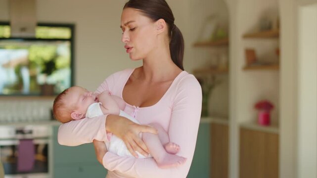 Exhausted mother gently rocking her restless baby while worrying about why he cannot fall asleep