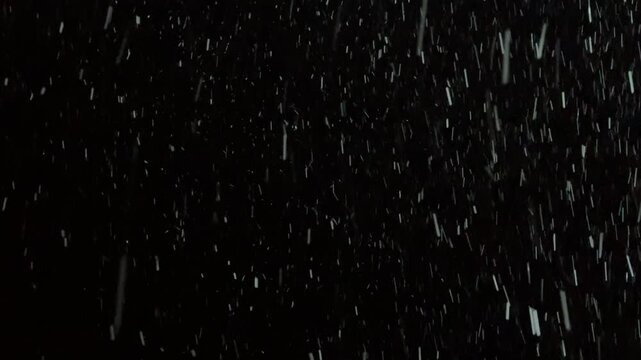 Heavy snowfall falling at night on a dark black background. Night snowfall concept.