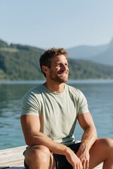 Fototapeta premium Man sitting on a lakeside dock smiling and enjoying the sun for lifestyle banner and travel background