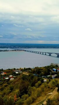 Vertical video. Saratov, Russia. The Saratov Bridge, a 2.8-kilometer prestressed concrete arch span across the Volga River, Drone footage under overcast skies. Drone footage. Rich colors