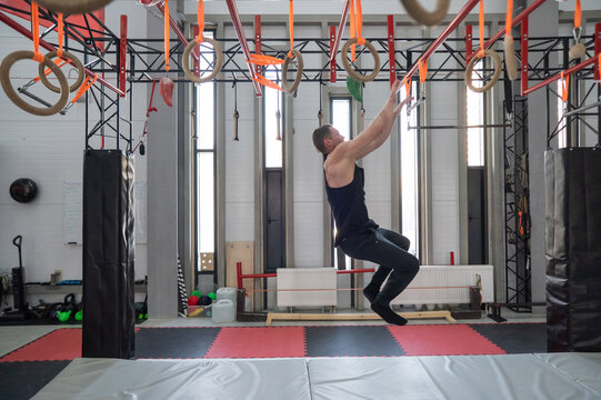 An athletic man practices at a ninja club's indoor obstacle course.