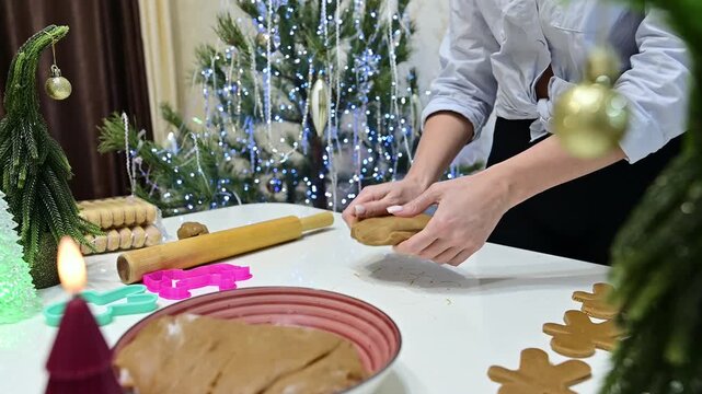 A woman is rolling dough to prepare gingerbread flatbread. The Christmas tree is in the background, and the table has decorations. It shows the joy of baking during the holiday season.