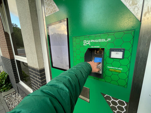den haag, netherlands - June 1 2022: A hand in a green jacket presses buttons on a Pharmaself 24 machine in Den Haag, Netherlands. This self-service transaction occurs during the day.