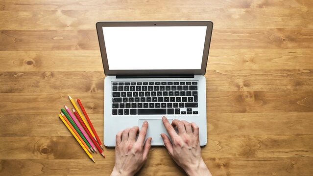 Top view of person working on laptop with blank screen on wooden desk for business planning 2027