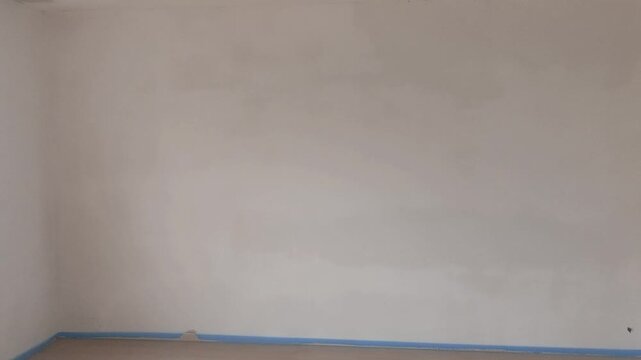 Freshly installed drywall with white primer paint on the wall in a room under renovation
