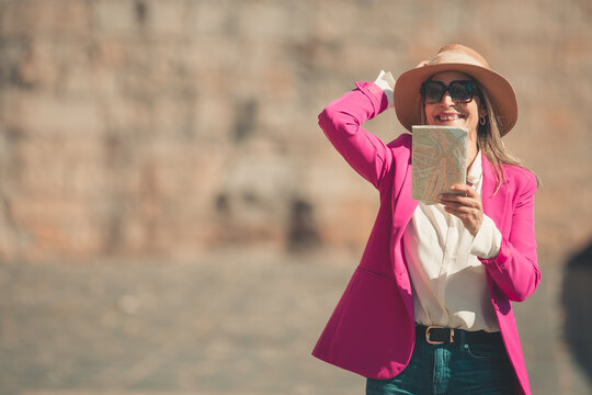 adult woman traveling with a map and hat in the street during summer
