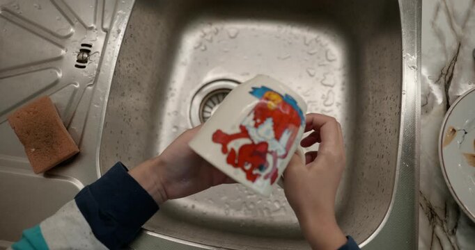 Close-up children's hands wash kitchen utensils sink and dishes. 4K 10-bit