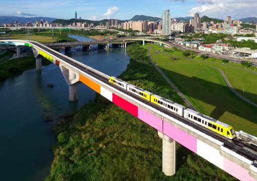 Aerial view of a train of Taipei Metro Circular Line traveling on a bridge across Xindian River and 101 Tower standing out amid buildings in downtown on a beautiful sunny day in Taipei, Taiwan