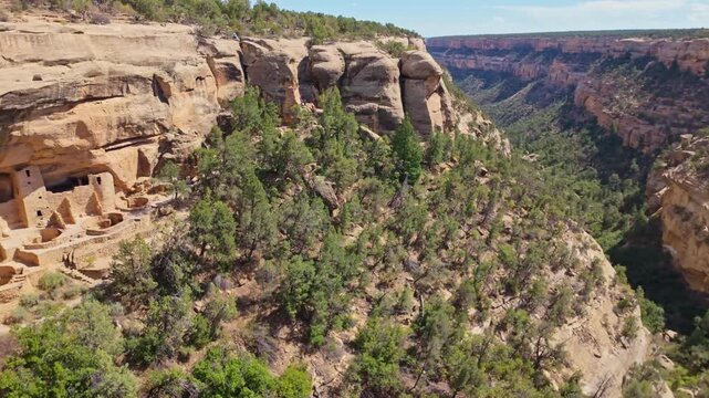 Warm sunset light illuminates ancient masonry dwellings nestled beneath towering sandstone cliffs at Mesa Verde Cliff Palace