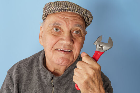 portrait vieil homme &acirc;g&eacute; avec clef &agrave; molette sur fond bleu