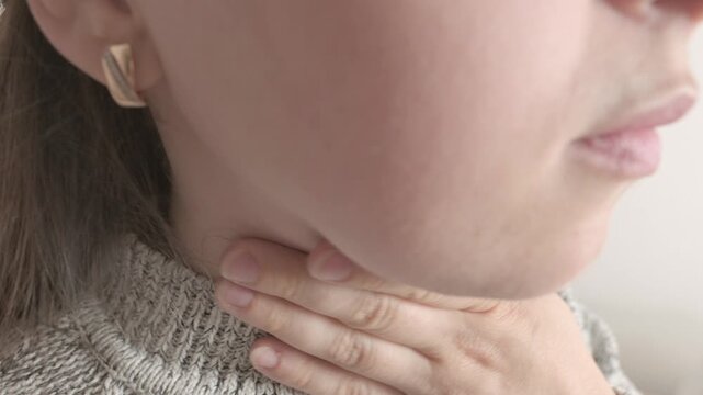 close-up young female neck, patient holding affected area, experiencing throat pain, Health concern, loss of voice, various causes, medical attention and treatment for condition, tonsillitis