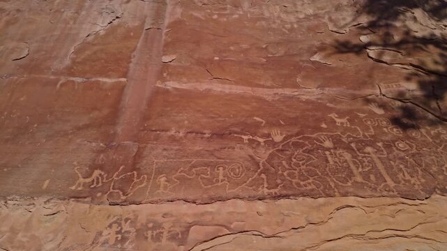 Intricate ancestral Native American rock carvings etched into sheer canyon sandstone walls flank Petroglyph Point Trail in Mesa Verde