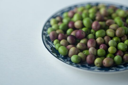 Fresh green and purple olives on a decorative ceramic plate