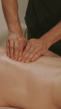massage therapist hands press palms and fingers into bare abdomen of person lying face-up on massage table