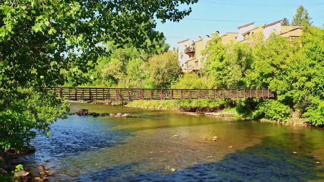 Warm golden sunlight illuminates the iconic pedestrian suspension bridge spanning the Animas River in Durango Colorado