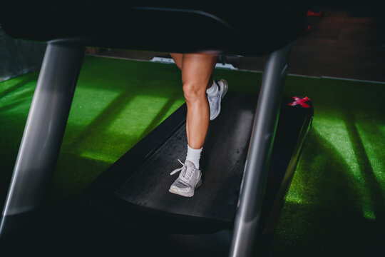 Active wellness functional fitness close up showcases muscular legs running on treadmill machine inside modern gym room, practicing high intensity workout cardio training routines daily